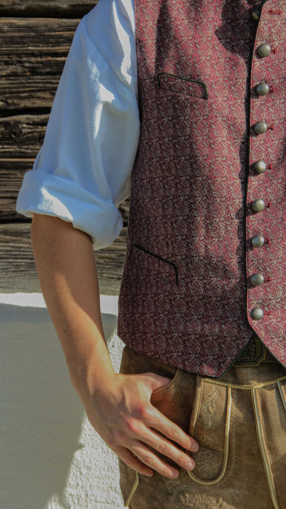 Männliches Model zu sehen in einem roten Jacket mit Muster und einer Lederhose